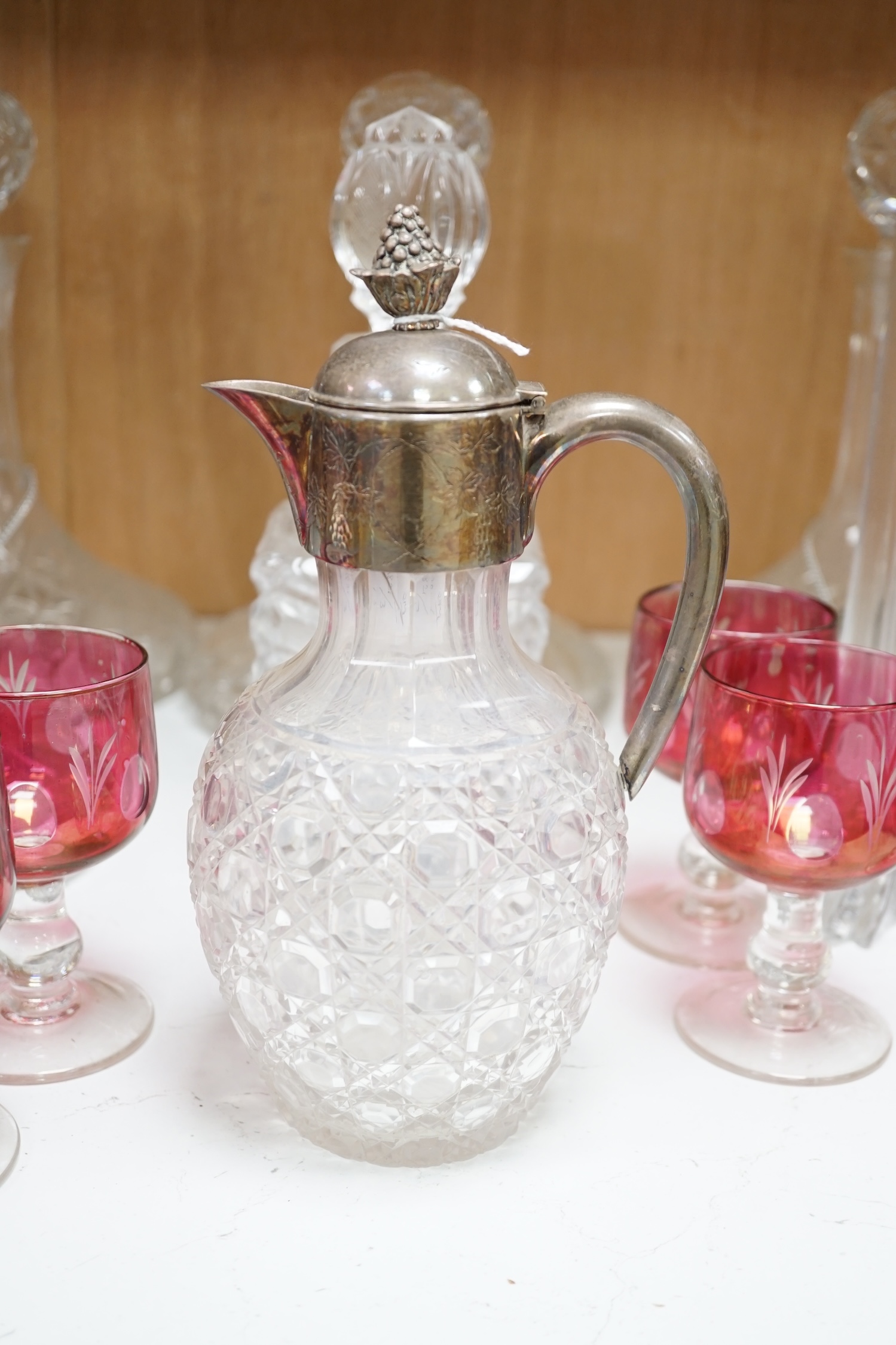 Two pairs of cut glass ships decanters, a square decanter, a ewer and a tall Scottish decanter and six cranberry glasses, tallest 43cm high